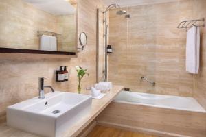 a bathroom with a white sink and a tub at NH Collection Madrid Palacio de Tepa in Madrid