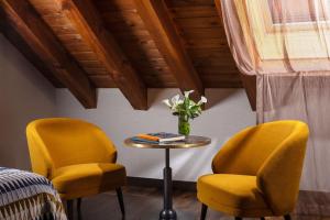two yellow chairs and a table with a vase of flowers at NH Collection Madrid Palacio de Tepa in Madrid