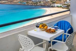 a table with a bowl of fruit and wine glasses and a beach at Sky Mariposa sospesa sul mare in Mindelo