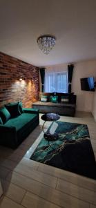 salon z zieloną kanapą i stołem w obiekcie Apartamenty Orchidea Łeba w Łebie