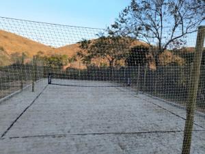 un campo da tennis di fronte a una recinzione di Chalés Jatobá ad Areias