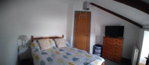 a bedroom with a bed and a dresser with a television at Sam's retreat in Hayle +3 photos