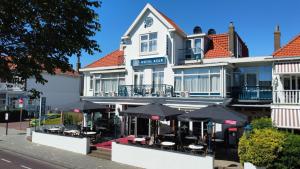 a hotel with tables and umbrellas in front of it at Hotel Keur in Zandvoort