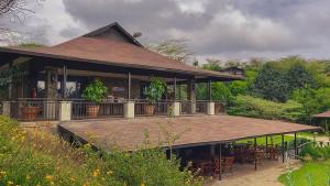 a building with a porch and tables and chairs at Ol-Kine Cottage at The Great Rift Valley Lodge & Golf Resort Naivasha in Naivasha