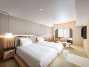 a bedroom with a large white bed and a television at Novotel Nara in Nara