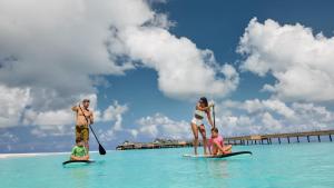 a group of people on surfboards in the ocean at JOALI Maldives in Raa Atoll