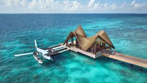 a plane is sitting on a dock in the water at JOALI Maldives in Raa Atoll