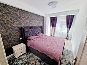 a bedroom with a bed with a purple comforter at DE Apartment in Rădăuţi