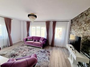 a living room with a purple couch and a tv at DE Apartment in Rădăuţi