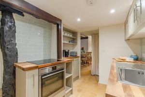 a kitchen with a stove top oven next to a sink at Spinner's Cottage in Burford