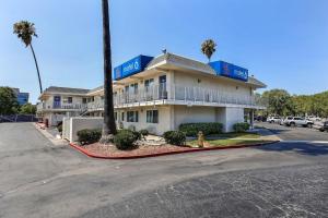 a hotel building with a palm tree and a parking lot at Motel 6-Pleasanton, CA in Pleasanton