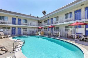 a pool in front of a hotel with chairs and umbrellas at Motel 6-Pleasanton, CA in Pleasanton