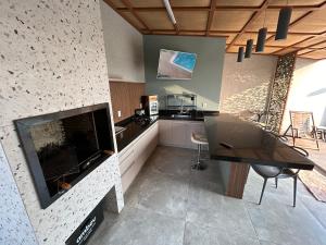 a living room with a fireplace and a table and a kitchen at Recanto Manga da Rosa - casinha de fazenda no centro da cidade in Olímpia