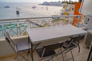 een tafel en stoelen op een balkon met uitzicht op het water bij Anja's Apartament in Sarandë +2 foto's