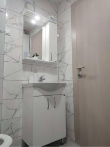 a white bathroom with a sink and a mirror at M apartman Kragujevac in Kragujevac +7 photos