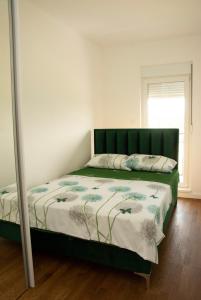 a bed with a green headboard in a bedroom at M apartman Kragujevac in Kragujevac