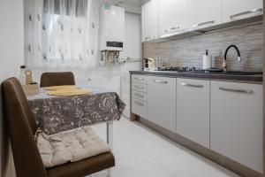 a kitchen with white cabinets and a table and a sink at Nordmark Studio One - Free Parking in Piteşti