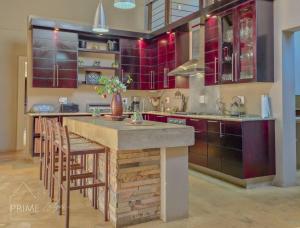 a kitchen with red cabinets and a counter with stools at Rhino Lodge at Zebula in Mabula