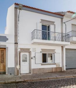 a white house with a balcony and a door at Casa Delgado in Tavira