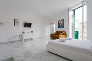 a large white room with a bed and a couch at Golden Suites by Dimorra in Naples