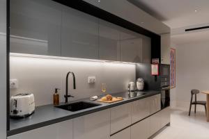 a kitchen with white cabinets and a sink with a toaster at Infinity Pool & Private Garden Oasis at Savoy Insular in Funchal +22 photos