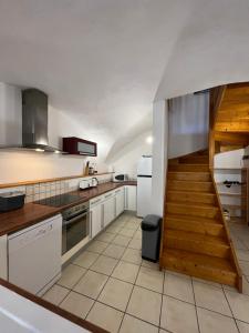 a kitchen with white cabinets and a wooden staircase at The Stable House Bourg d’Oisans -bike/hike/ski in Le Bourg-dʼOisans