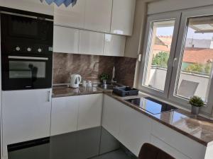 兹雷尼亚宁Apartman LUX的厨房配有白色橱柜、水槽和窗户