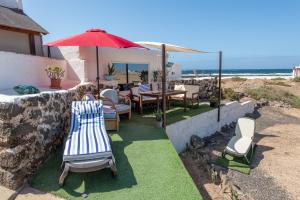 a patio with a table and chairs and an umbrella at Casa Cueva in La Oliva
