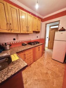 a kitchen with wooden cabinets and a white refrigerator at Apartamento terraza con vistas al mar in M'diq