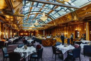 a restaurant with tables and chairs and a glass ceiling at Grand Hotel Zermatterhof in Zermatt