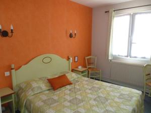 een slaapkamer met een bed met een oranje muur bij Hôtel de la Poste in Chagny