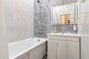 a bathroom with a white tub and a sink and a mirror at Трех комнатные апартаменты в новом доме рядом с Батырмол in Pavlodar