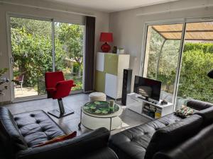 sala de estar con sofás de cuero y TV en La Maison sous l'olivier, en Morières-lès-Avignon