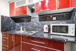 eine Küche mit roten Schränken und einer Mikrowelle in der Unterkunft Трехкомнатная квартира рядом с ЖД вокзалом in Pawlodar + 8 Fotos