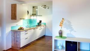 uma cozinha com armários brancos e um vaso de flores sobre uma mesa em Appartementhaus Fritz-Rosenkranz em Mariapfarr