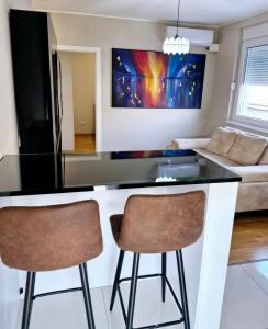 兹雷尼亚宁Apartman LUX的厨房配有柜台和2个酒吧凳