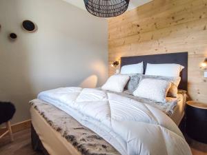 ein Schlafzimmer mit einem großen Bett mit einer Holzwand in der Unterkunft Superbe chalet duplex 3* avec prestations hôtelières, pied de pistes, parking, wifi - FR-1-356-378 in Les Avanchers