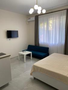 a room with a bed and a couch and a tv at New House Gonio in Batumi