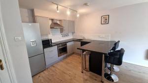 a kitchen with white cabinets and a black counter top at Cosy 2BR Modern Apt with Free Parking in Liverpool