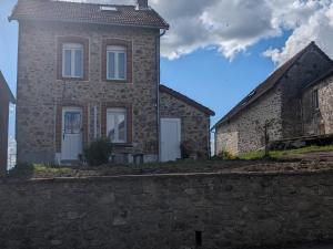 a stone house with a stone wall next to a building at Maison agréable 4 à 6 pers in Aulon
