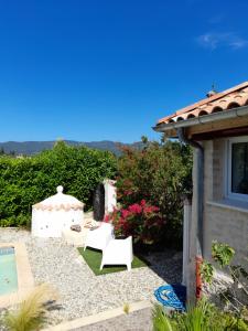 a garden with two white chairs and a pool at tonelle in Montélimar
