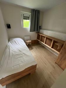a bedroom with a bed and wooden floors and a window at Chalet 't Zwaluwnest in Aagtekerke