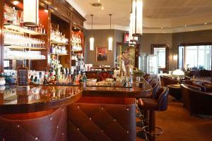 a bar in a restaurant with a counter and chairs at Morada Strandhotel Ostseebad Kühlungsborn in Kühlungsborn