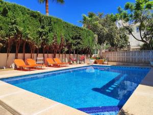 a swimming pool with orange chairs and a fence at BEACH VILLA with PRIVATE POOL in Palma de Mallorca