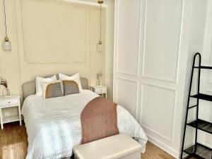 een witte slaapkamer met een bed en een stoel bij Eleven Arene BY PRIMO C0NCIERGERIE in Bourges