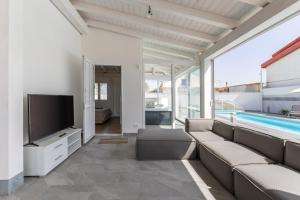 a living room with a couch and a tv and a pool at Villa Maria con piscina riscaldata in Santa Maria Del Focallo