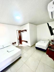a hotel room with two beds and a television at Vento Leste Suites in Flecheiras