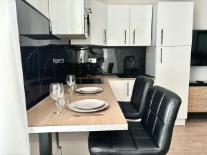 een keuken met een tafel, zwarte stoelen en witte kasten bij Eleven Arene BY PRIMO C0NCIERGERIE in Bourges +13 foto's