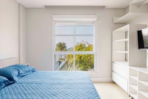 a bedroom with a blue bed and a window at Apartamento em Condomínio com Piscina e Jacuzzi - Boulevard Bombinhas in Bombinhas +17 photos