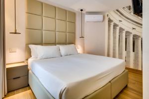 a bedroom with a large white bed with a wall at Relais Badoer in Rome